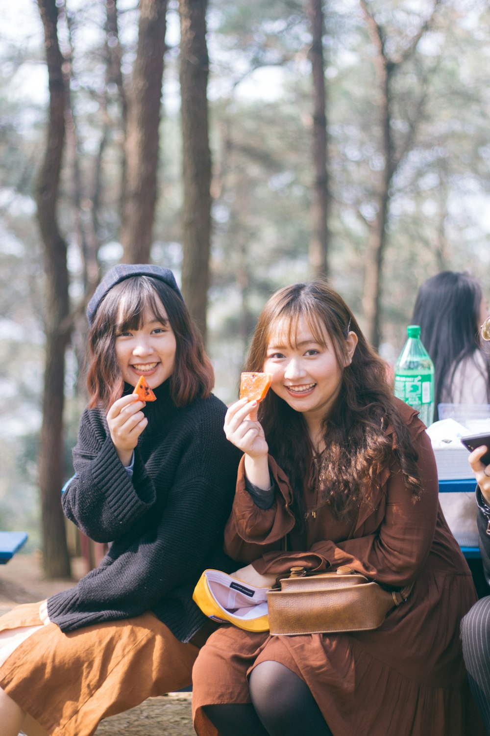 duas mulheres segurando batatas fritas enquanto sentadas e sorriem