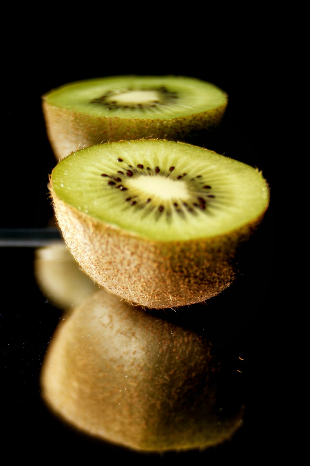 kiwi sliced in half on black reflective surface