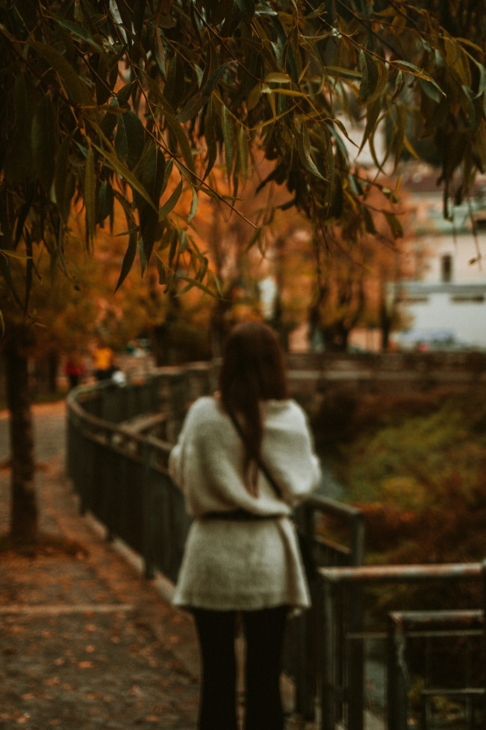 woman wearing white jacket standing while facing back near railings