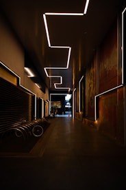 a dimly lit hallway with benches and a painting on the wall