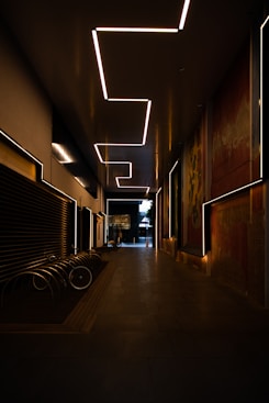 a dimly lit hallway with benches and a painting on the wall