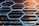 Geometric patterns of hexagons made from metal or plastic align parallel to a series of horizontal slats, possibly forming part of a building façade with a modern architectural design.