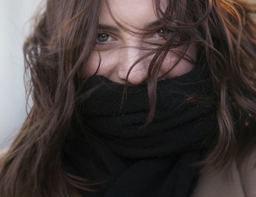 woman smiling and looking at the camera with scarf covering her mouth