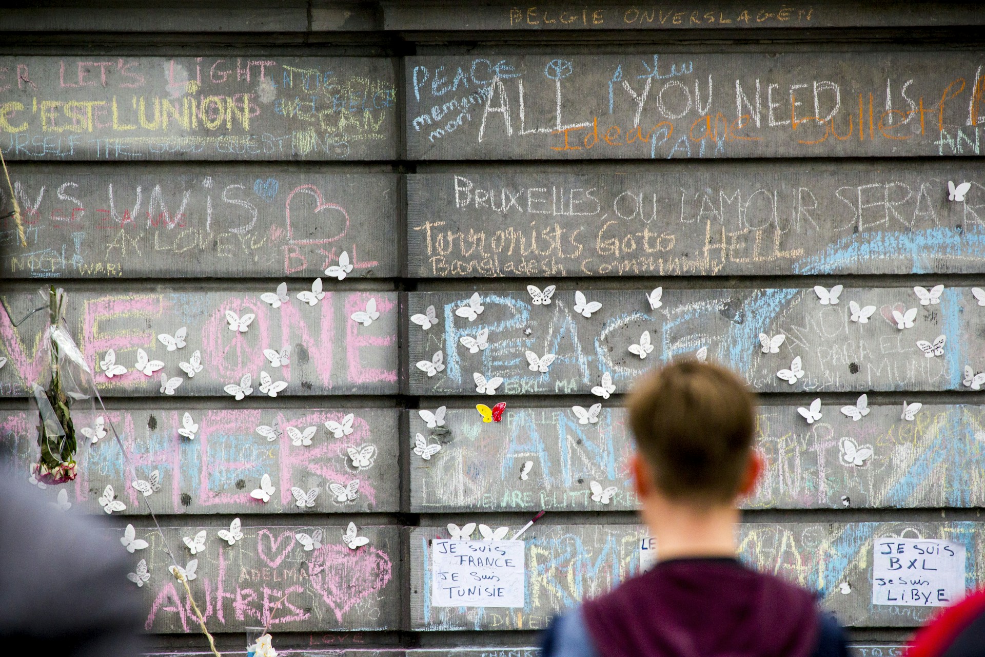 a young boy standing in front of a wall covered in graffiti