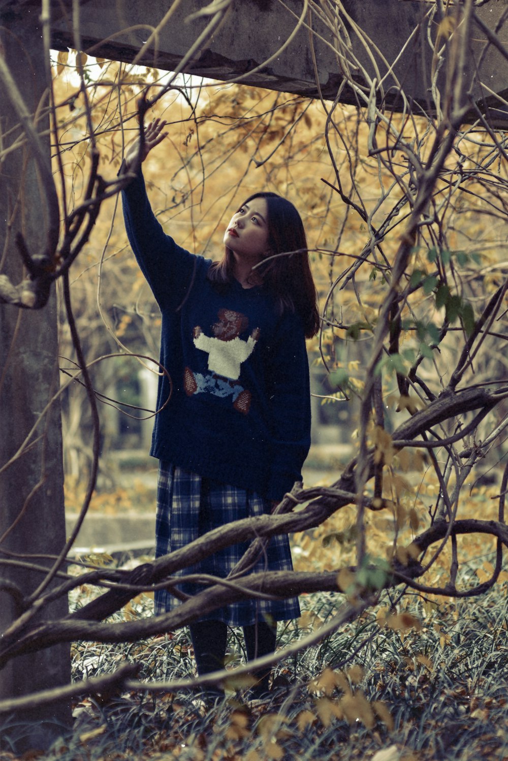 woman standing below bridge with vines