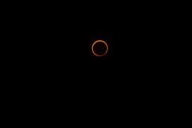 A dark background with a bright, glowing orange ring in the center, evoking a solar eclipse.
