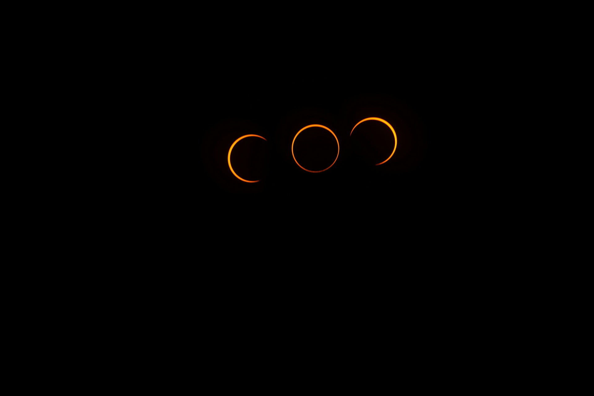 a black background with three eclipses in the sky