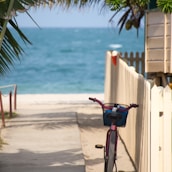 bike parks near white fence in front of the beach
