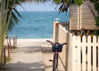 bike parks near white fence in front of the beach