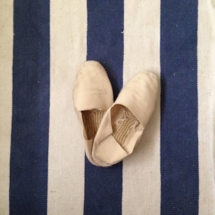 Casual slip-on flats in neutral beige resting on a cozy knitted blanket.