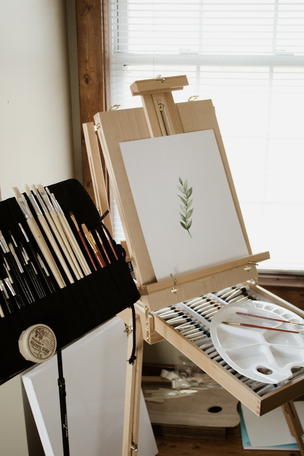 paint brushes beside a French easel and paint canvass