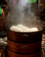 Steamed momos neatly stacked in a bamboo steamer with steam gently rising.