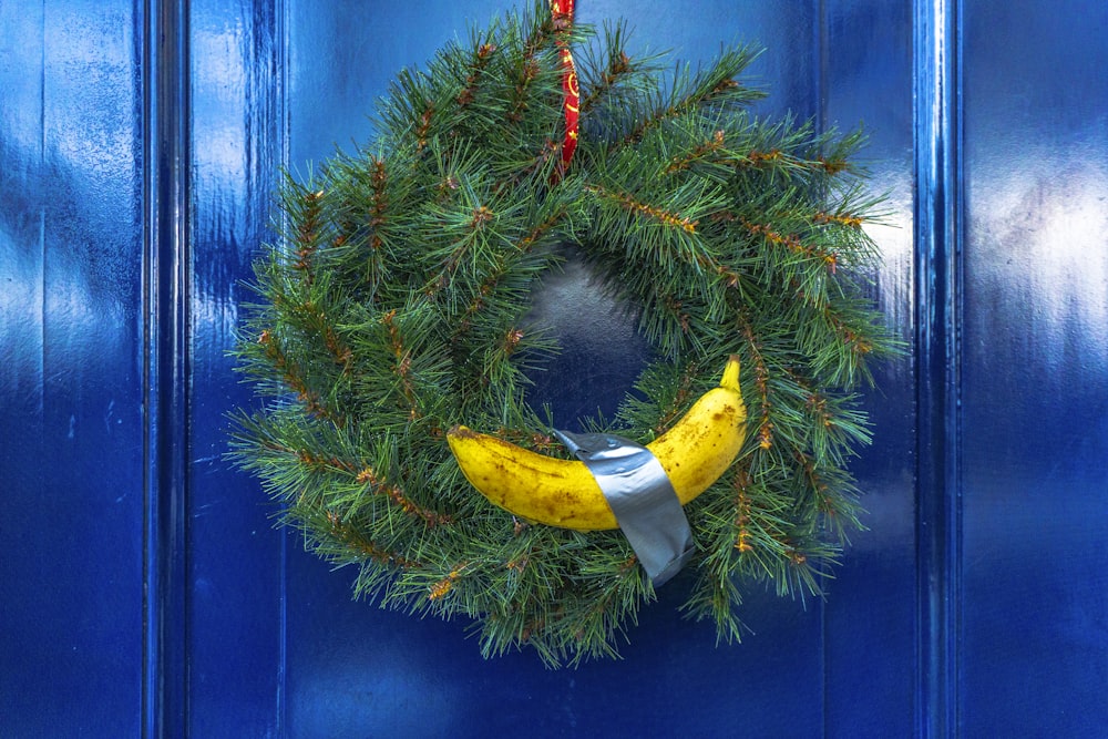 green spruce wreath with yellow banana hanging on a blue door