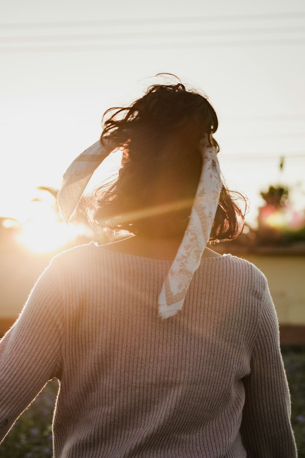 woman in gray sweater standing in front of sunlight