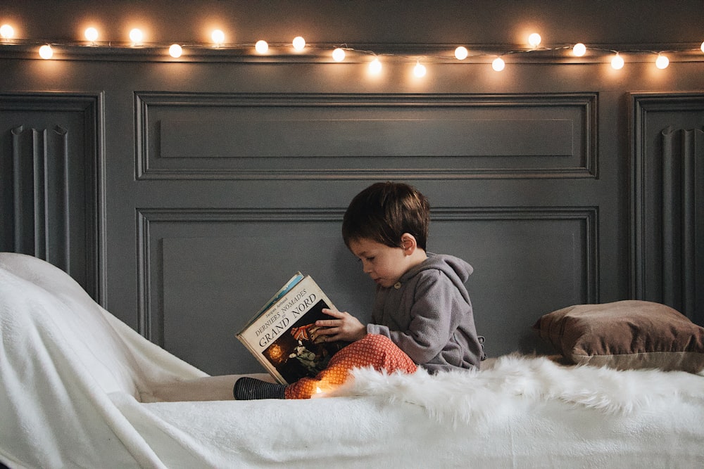 boy reading book on bed