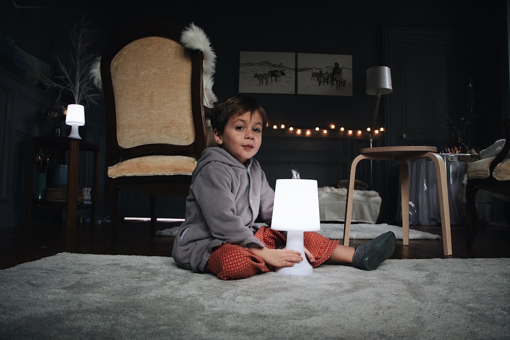 boy sitting in the floor holding a lamp