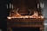 A rustic fireplace mantle is adorned with antler decorations and lit by a string of small warm lights. Ornate candle holders with tall white candles flank the antlers on each side, contributing to a vintage ambiance.
