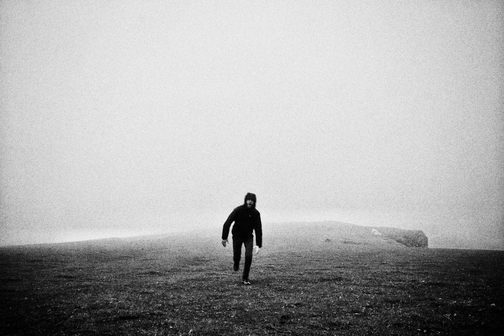 grayscale photography of man running in an open field