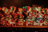 Children performing energetically on stage in traditional Canarian carnival costumes with bright red and black colors