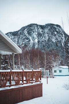 A sturdy wooden deck dusted with fresh snow, overlooking a vast Alaskan forest.