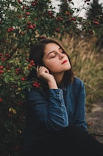 A serene woman sitting peacefully in nature, eyes closed, embracing calm.