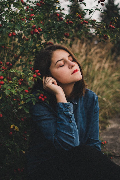 A serene woman sitting peacefully in nature, reflecting and feeling calm.