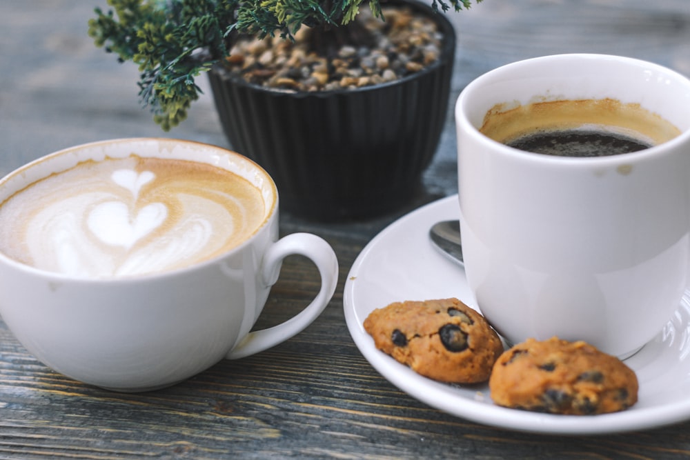 xícara de café preto e dois biscoitos no pires