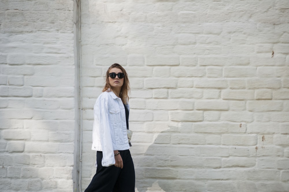 a woman standing in front of a white brick wall