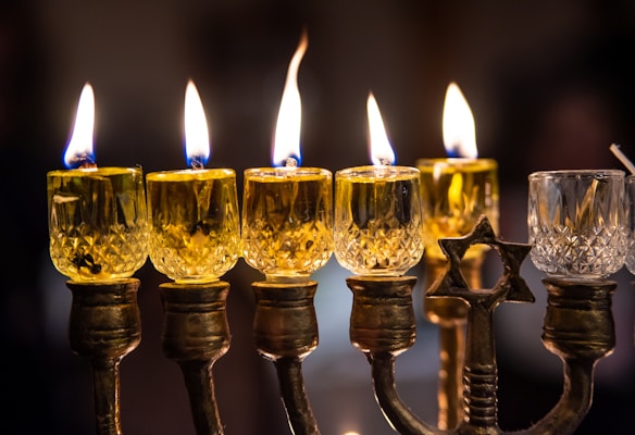 An elegant Jewish candelabra holding lit candles, casting warm shadows on a festive table.