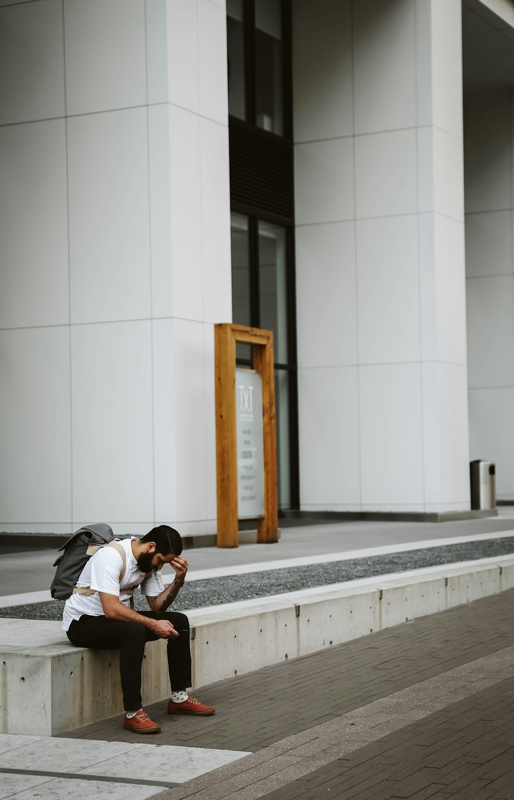 man in white shirt and black pants sitting outdoors