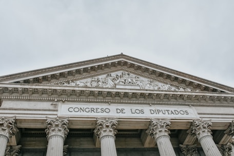 The image features the facade of an imposing classical building with large columns and a detailed pediment. The words 'CONGRESO DE LOS DIPUTADOS' are inscribed prominently on the structure, indicating its governmental function.