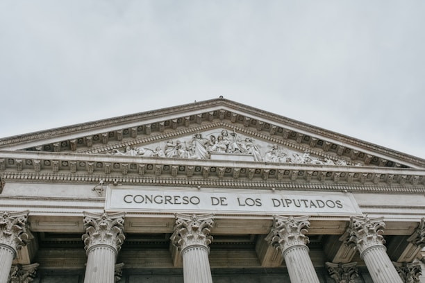 The image features the facade of an imposing classical building with large columns and a detailed pediment. The words 'CONGRESO DE LOS DIPUTADOS' are inscribed prominently on the structure, indicating its governmental function.