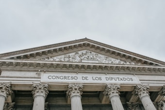 The image features the facade of an imposing classical building with large columns and a detailed pediment. The words 'CONGRESO DE LOS DIPUTADOS' are inscribed prominently on the structure, indicating its governmental function.