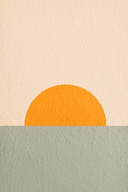 A minimalist artwork featuring a simple geometric design. An orange semicircle, resembling a setting sun, is positioned at the horizon line where two textured color blocks meet. The upper portion is a light cream color, while the lower section is a muted green shade.