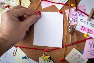 shallow focus photo of white paper sheet mounted on cork board