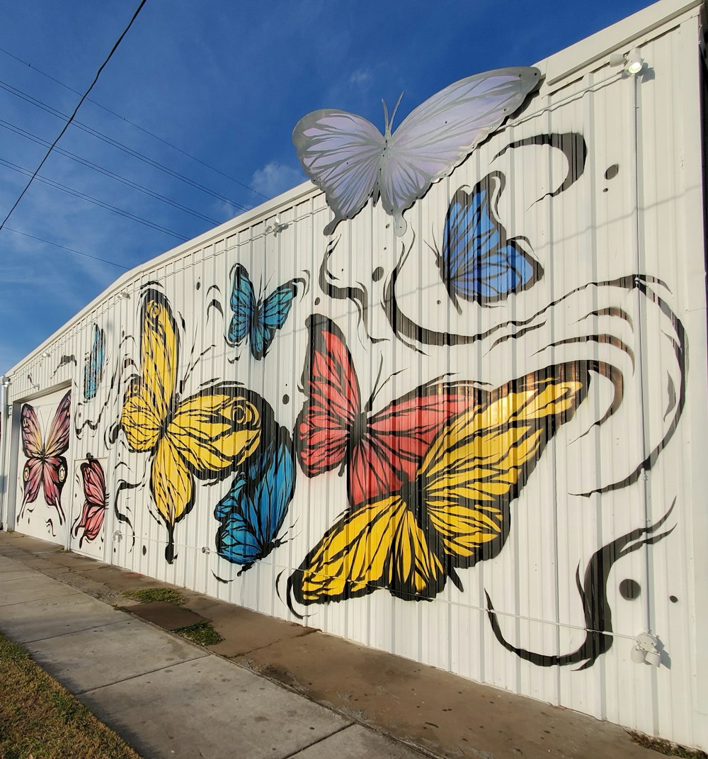 white wall with multicolored butterflies art under blue and white sky