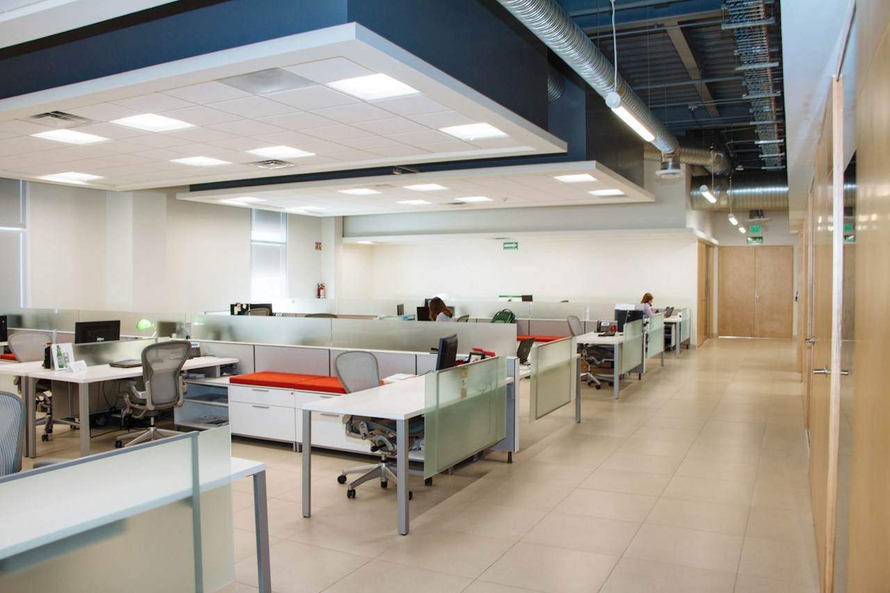 Open-plan office with rows of white desks and no one at them