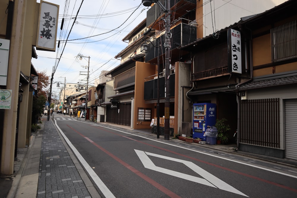 gray road with no vehicle near buildings under white and blue sky