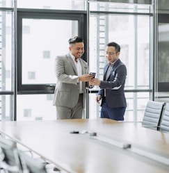 two men shaking hands in a conference room