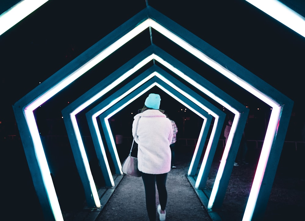 a woman in a white coat is walking through a tunnel