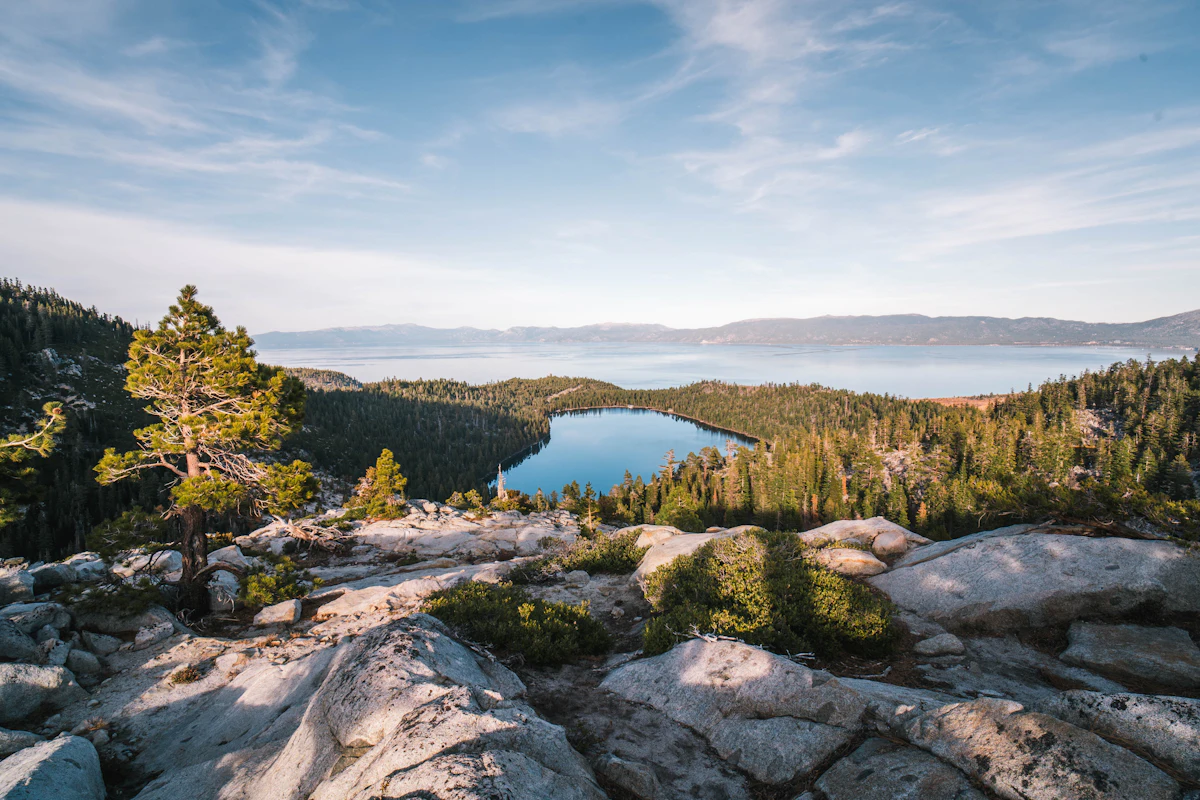 Granite slabs and a lone pine above a small lake near Emerald Bay, with Lake Tahoe beyond