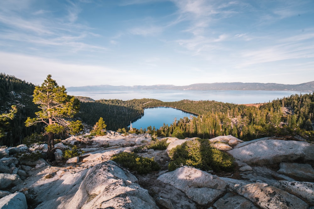 formaciones rocosas que ven el lago rodeado de árboles verdes bajo el cielo blanco y azul