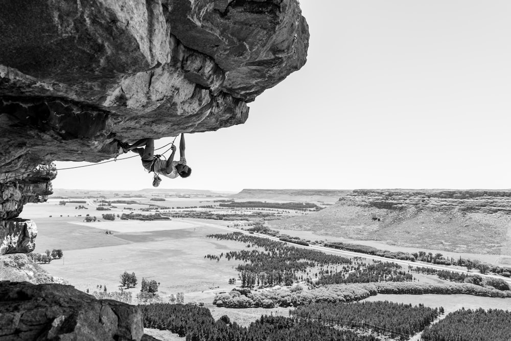 grayscale photography of man climbing on mountain