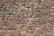 A neatly arranged stone wall with variously sized and colored rectangular stones. The stones have an uneven surface, and their colors range from shades of gray to hints of orange and brown. The mortar between the stones is visible and evenly applied.