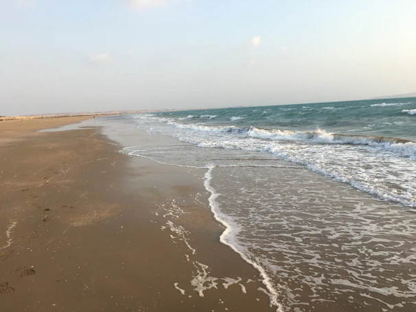 A peaceful beach scene with gentle waves and footprints in the sand.