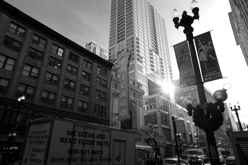 grayscale photography of different vehicles on road near buildings