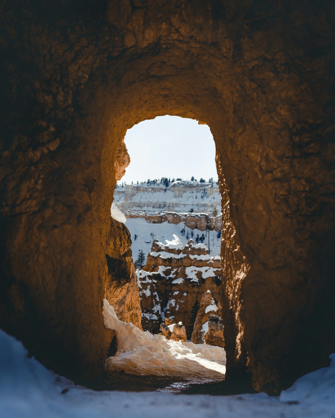 arch cave covered with snow during daytime