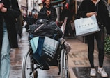 A caregiver running errands with a client, carrying groceries together on a bright city street in Boston.