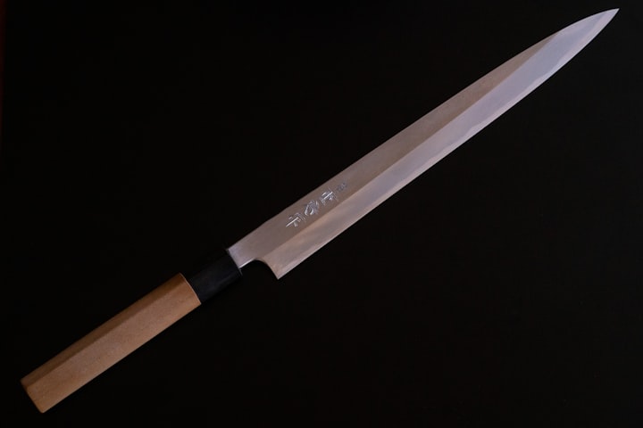 A close-up of a Damascus blade with a brown wooden handle, scaled to the small-format utility cut of a petty knife