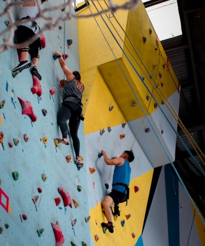 three people climbing on wall